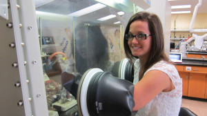 Mount Allison chemistry student Jessica Miller works in the ‘glove box’ in Dr. Steve Westcott’s chemistry lab. Miller will be examining boron and platinum as novel approaches to the treatment of breast cancer as her summer research project.